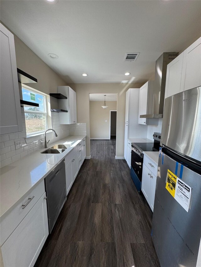 kitchen with wall chimney exhaust hood, stainless steel appliances, sink, and white cabinets