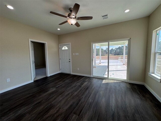 unfurnished living room with dark wood-type flooring, ceiling fan, and plenty of natural light