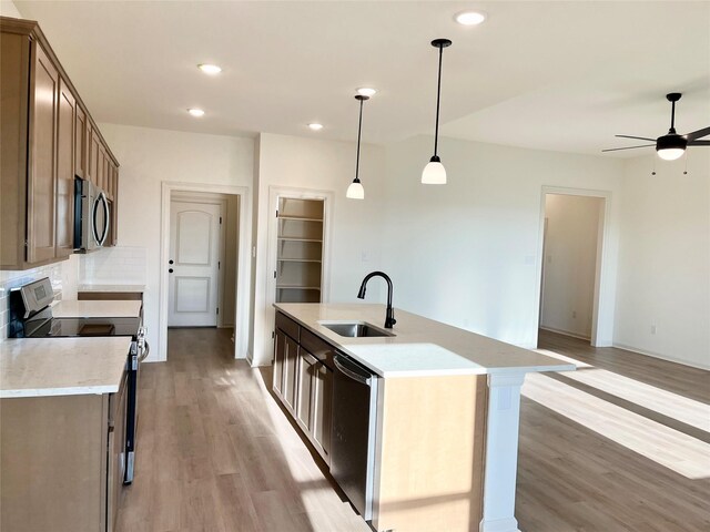 726 Blue Sky Pl, Beasley, TX 77417 - kitchen with appliances with stainless steel finishes, a sink, light wood finished floors, a ceiling fan, and tasteful backsplash
