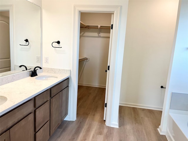 726 Blue Sky Pl, Beasley, TX 77417 - bathroom featuring wood finished floors, a spacious closet, double vanity, a bathtub, and baseboards