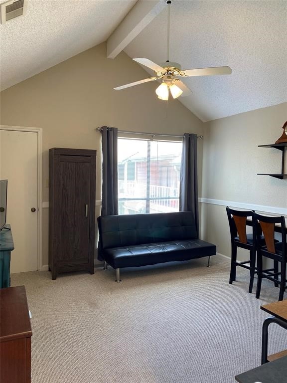 living room with ceiling fan, vaulted ceiling with beams, and light carpet