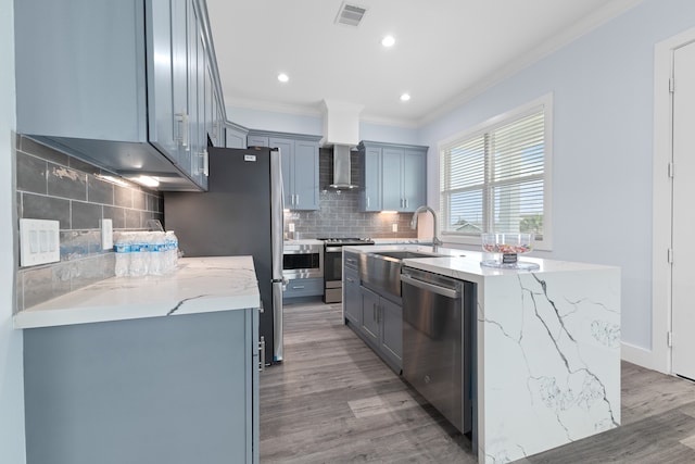 kitchen featuring light wood-type flooring, appliances with stainless steel finishes, an island with sink, and tasteful backsplash