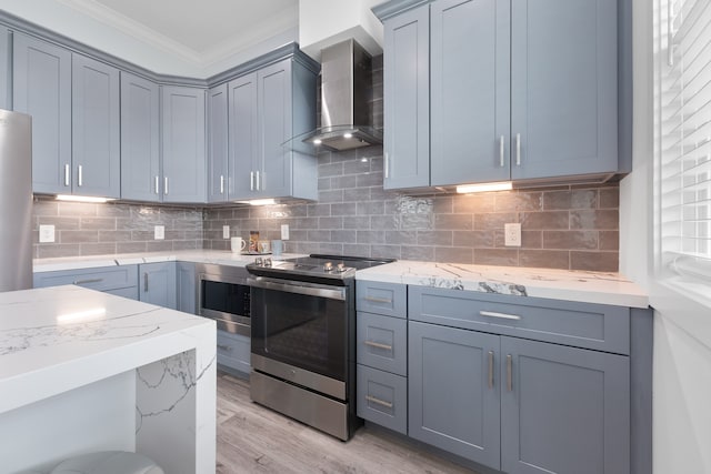 kitchen featuring light hardwood / wood-style flooring, wall chimney range hood, light stone counters, and range with electric stovetop