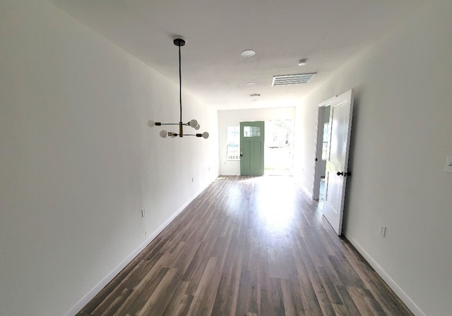 hall featuring dark hardwood / wood-style floors and a chandelier