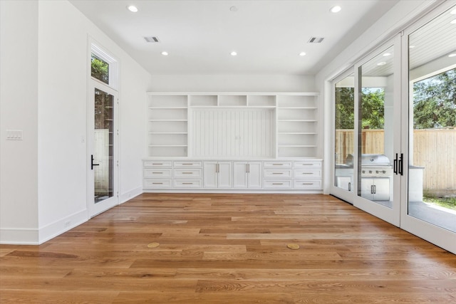 spare room featuring french doors, light hardwood / wood-style floors, and a healthy amount of sunlight