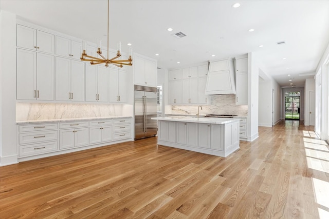 kitchen featuring custom range hood, light hardwood / wood-style flooring, built in refrigerator, and white cabinets