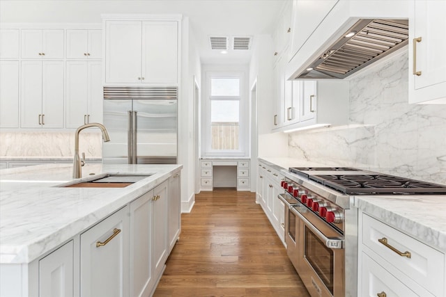 kitchen featuring sink, premium appliances, light hardwood / wood-style flooring, backsplash, and custom range hood