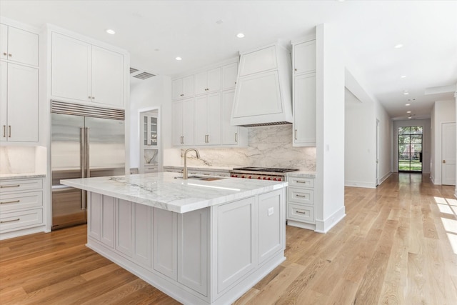 kitchen with an island with sink, stainless steel appliances, sink, and light hardwood / wood-style flooring