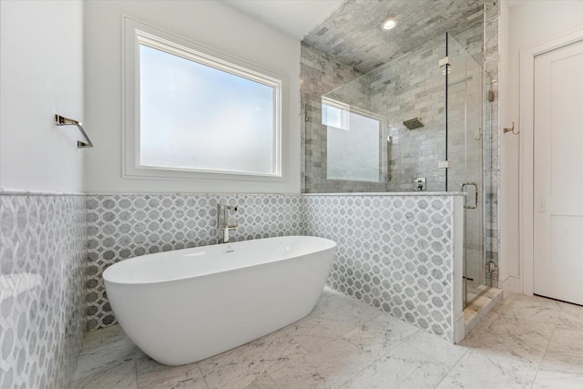 bathroom with plus walk in shower, sink, and tile walls