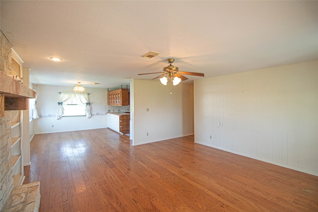 unfurnished living room featuring ceiling fan, wood-type flooring, and a fireplace