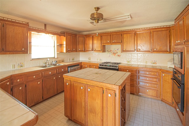 kitchen with a kitchen island, ceiling fan, appliances with stainless steel finishes, backsplash, and tile counters