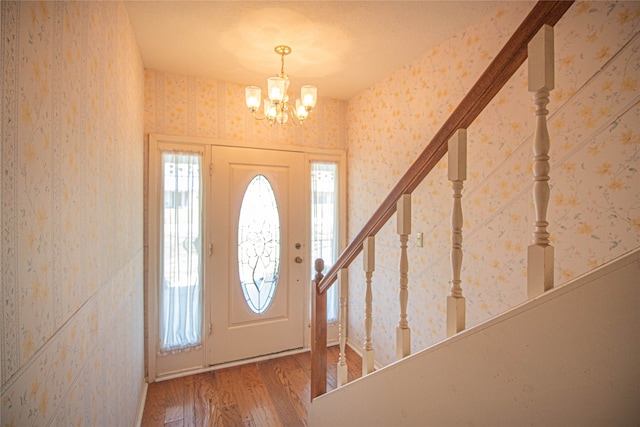 foyer entrance featuring a notable chandelier, a wealth of natural light, and wood-type flooring