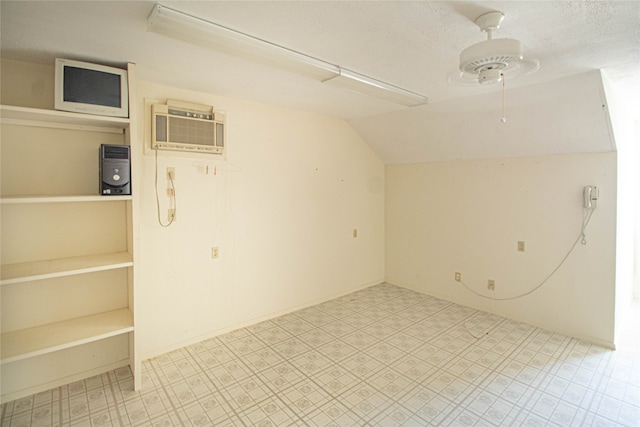 additional living space with lofted ceiling, ceiling fan, light tile flooring, and a wall unit AC