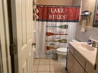 bathroom featuring toilet, tile flooring, and vanity