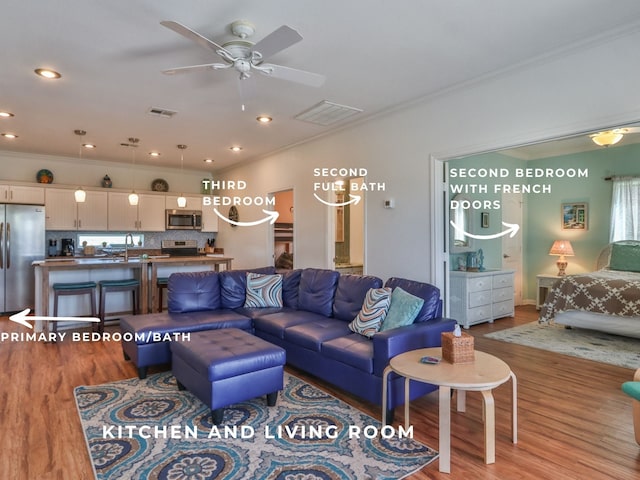 living room featuring hardwood / wood-style floors, ceiling fan, sink, and crown molding