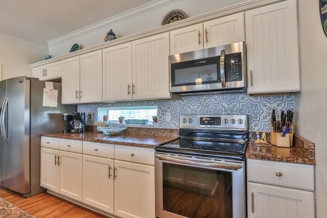 kitchen featuring backsplash, ornamental molding, light hardwood / wood-style floors, and appliances with stainless steel finishes