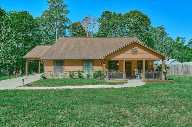 exterior space featuring stone siding, an attached carport, covered porch, fence, and a front yard