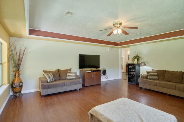 living room with a ceiling fan, visible vents, dark wood finished floors, and baseboards