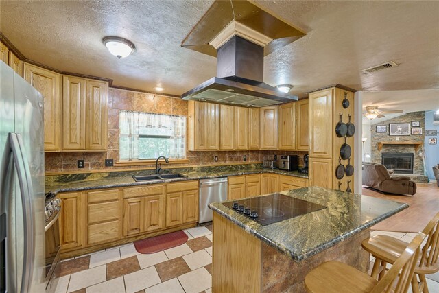 kitchen featuring light tile patterned flooring, a breakfast bar, ceiling fan, stainless steel appliances, and a fireplace