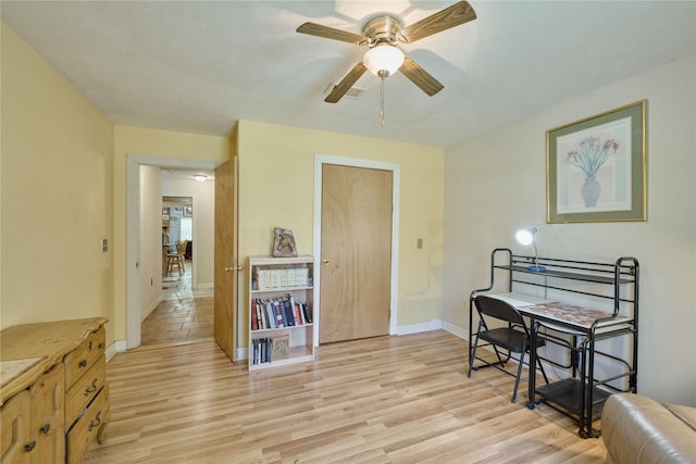 sitting room featuring baseboards, a ceiling fan, and light wood-style floors