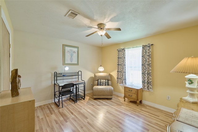 sitting room with light wood-style floors, visible vents, and baseboards