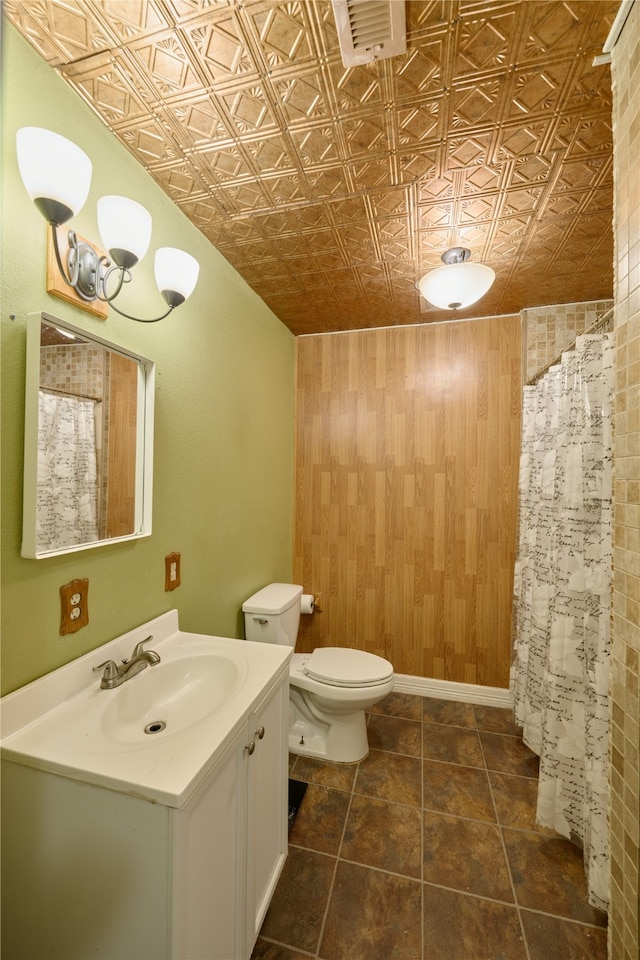 bathroom featuring tile patterned floors, vanity, wooden walls, and toilet