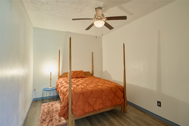 bedroom featuring dark wood-type flooring, ceiling fan, and a textured ceiling