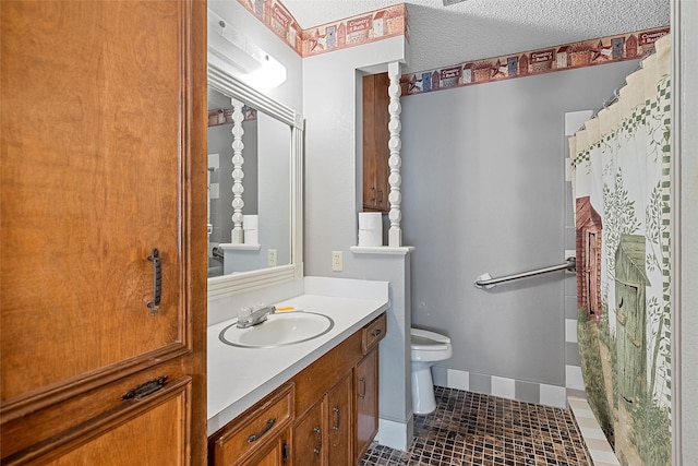 bathroom with tile floors, toilet, large vanity, and a textured ceiling