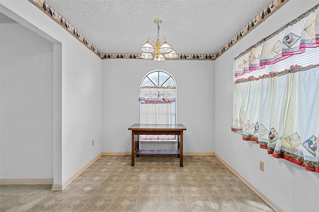 interior space featuring a textured ceiling and a chandelier