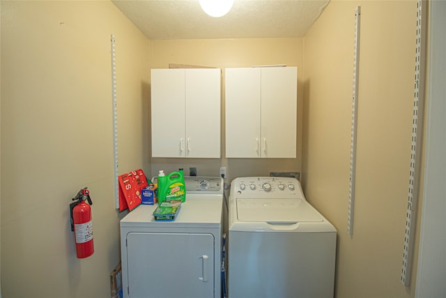 laundry area with a textured ceiling, washer and clothes dryer, and cabinets