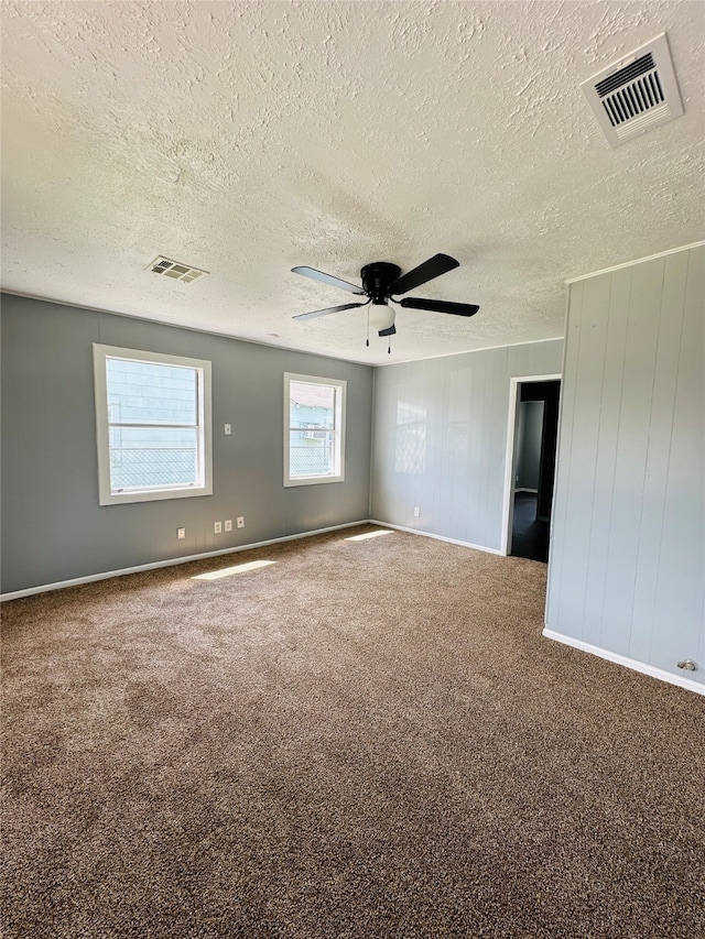 carpeted spare room with a textured ceiling and ceiling fan