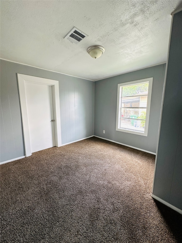 carpeted empty room with a textured ceiling