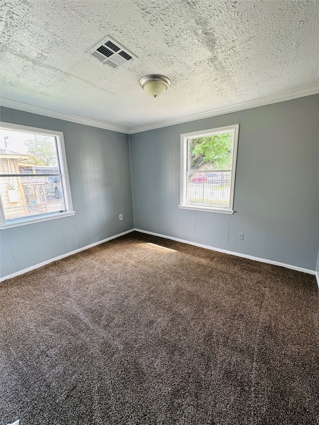 unfurnished room featuring a healthy amount of sunlight, dark colored carpet, a textured ceiling, and crown molding