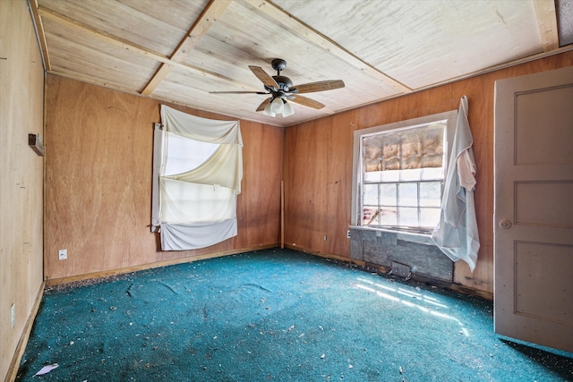 carpeted spare room with wooden walls, wood ceiling, and ceiling fan