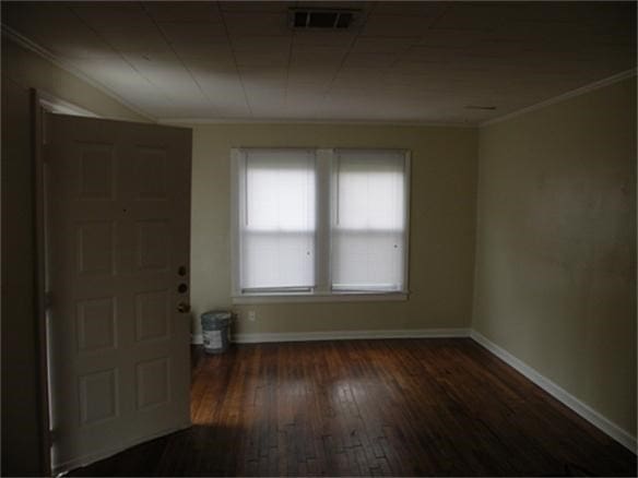 empty room with crown molding and dark hardwood / wood-style flooring