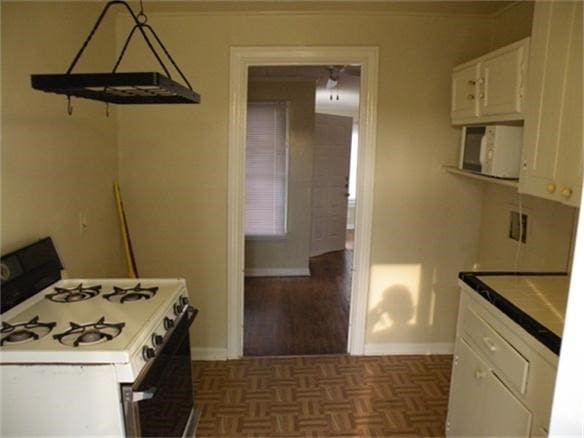 kitchen featuring dark parquet flooring, white appliances, and white cabinetry