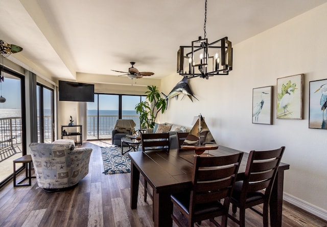 dining space featuring dark hardwood / wood-style flooring, a water view, and ceiling fan with notable chandelier