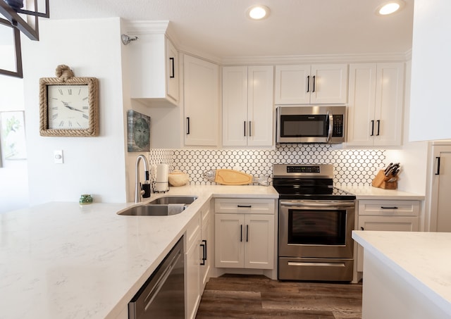 kitchen with dark wood-type flooring, stainless steel appliances, sink, white cabinetry, and light stone countertops