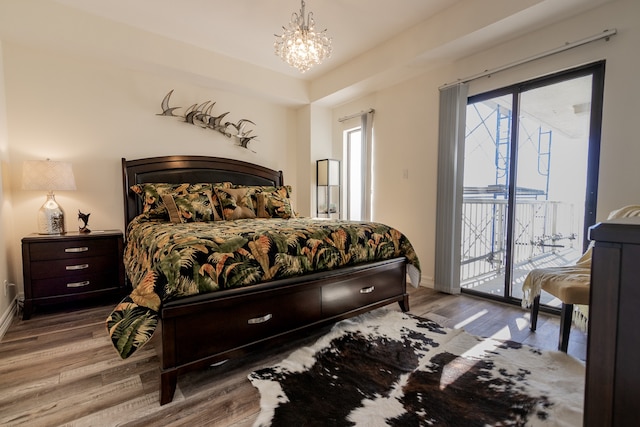 bedroom featuring hardwood / wood-style floors, a notable chandelier, and access to outside