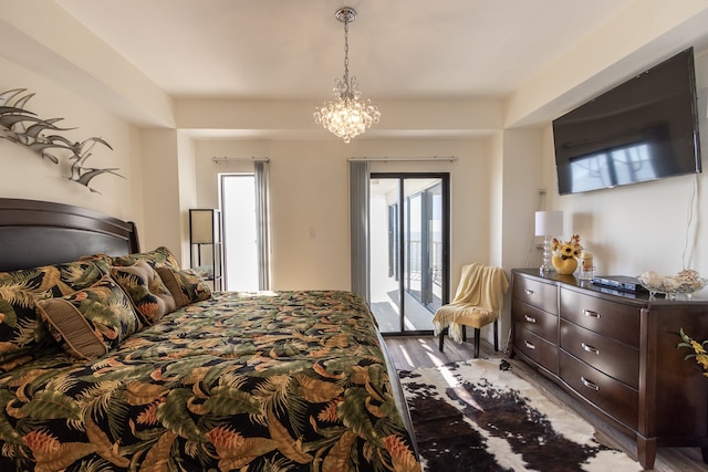 bedroom with an inviting chandelier, access to exterior, and hardwood / wood-style flooring