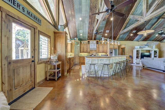 kitchen with high vaulted ceiling, stainless steel fridge, ceiling fan, and a breakfast bar