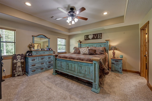 carpeted bedroom featuring a tray ceiling and ceiling fan