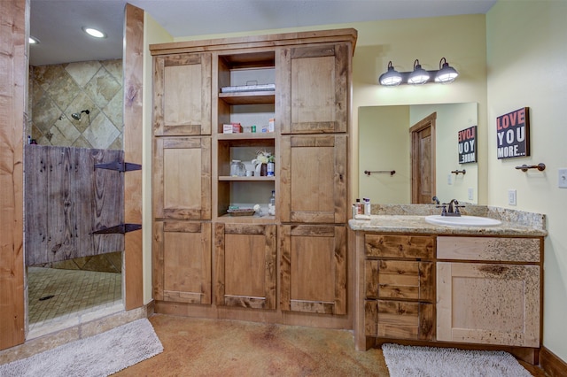 bathroom featuring tiled shower and large vanity