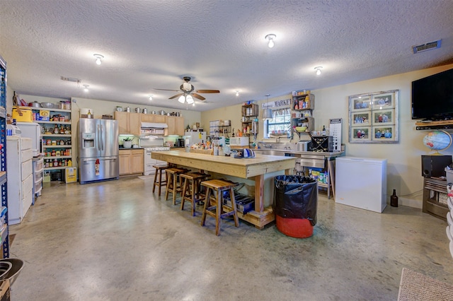 kitchen featuring ceiling fan, light brown cabinets, white appliances, and a textured ceiling