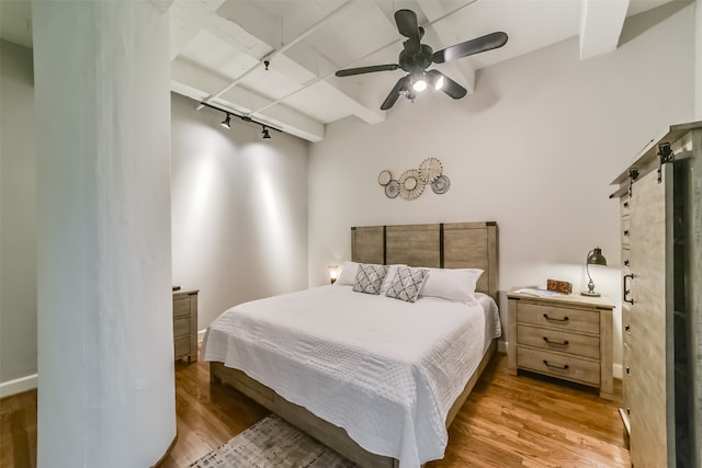 bedroom with a barn door, light wood-type flooring, and ceiling fan