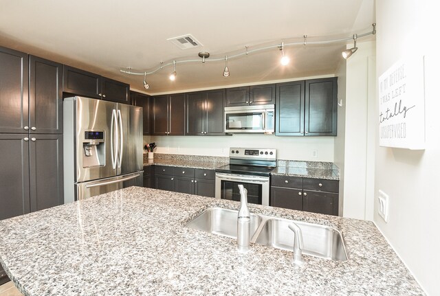 kitchen featuring light stone countertops, stainless steel appliances, and rail lighting