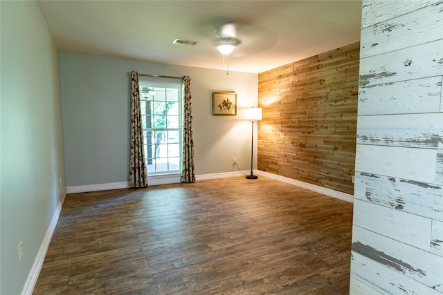 unfurnished room with ceiling fan, wood walls, and hardwood / wood-style flooring