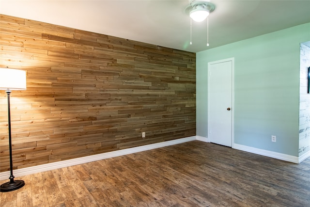 spare room featuring ceiling fan, wood walls, and hardwood / wood-style flooring