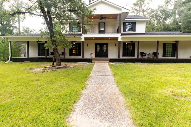 view of front facade with ceiling fan, a balcony, covered porch, and a front yard