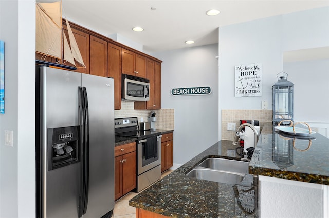 kitchen featuring dark stone counters, stainless steel appliances, backsplash, light tile floors, and sink